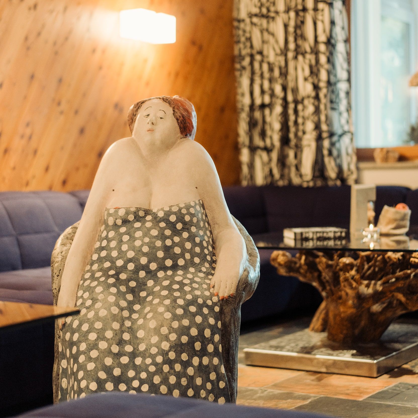 Eine skurrile Statue sitzt elegant im Glemmtalerhof, umgeben von modernem Design und rustikalem Charme.