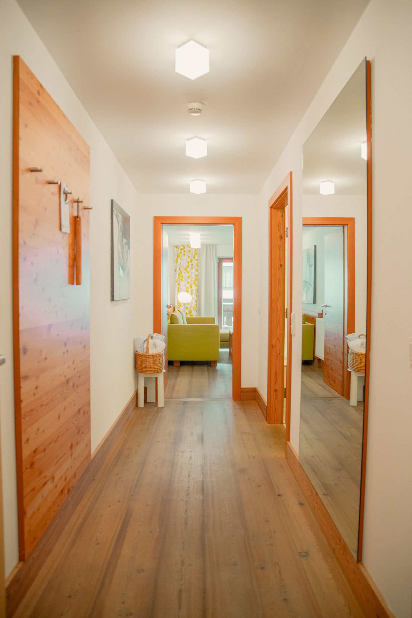 Ein heller Flur im Glemmtalerhof in Hinterglemm mit einem gemütlichen Wohnzimmer im Hintergrund. DE