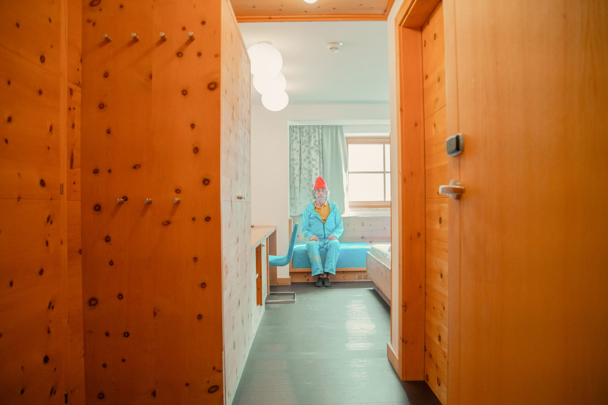 Ein gemütliches Zimmer im Glemmtalerhof in Hinterglemm mit Holzdetails und einem Mann in blauer Kleidung. DE