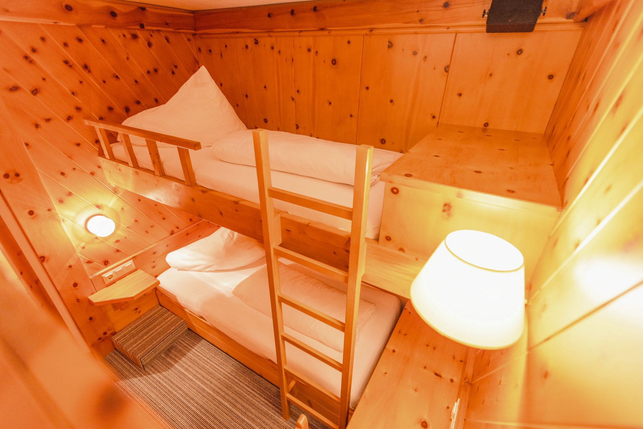 Ein gemütliches Zimmer im Glemmtalerhof mit zwei Etagenbetten und warmen Holzverkleidungen.