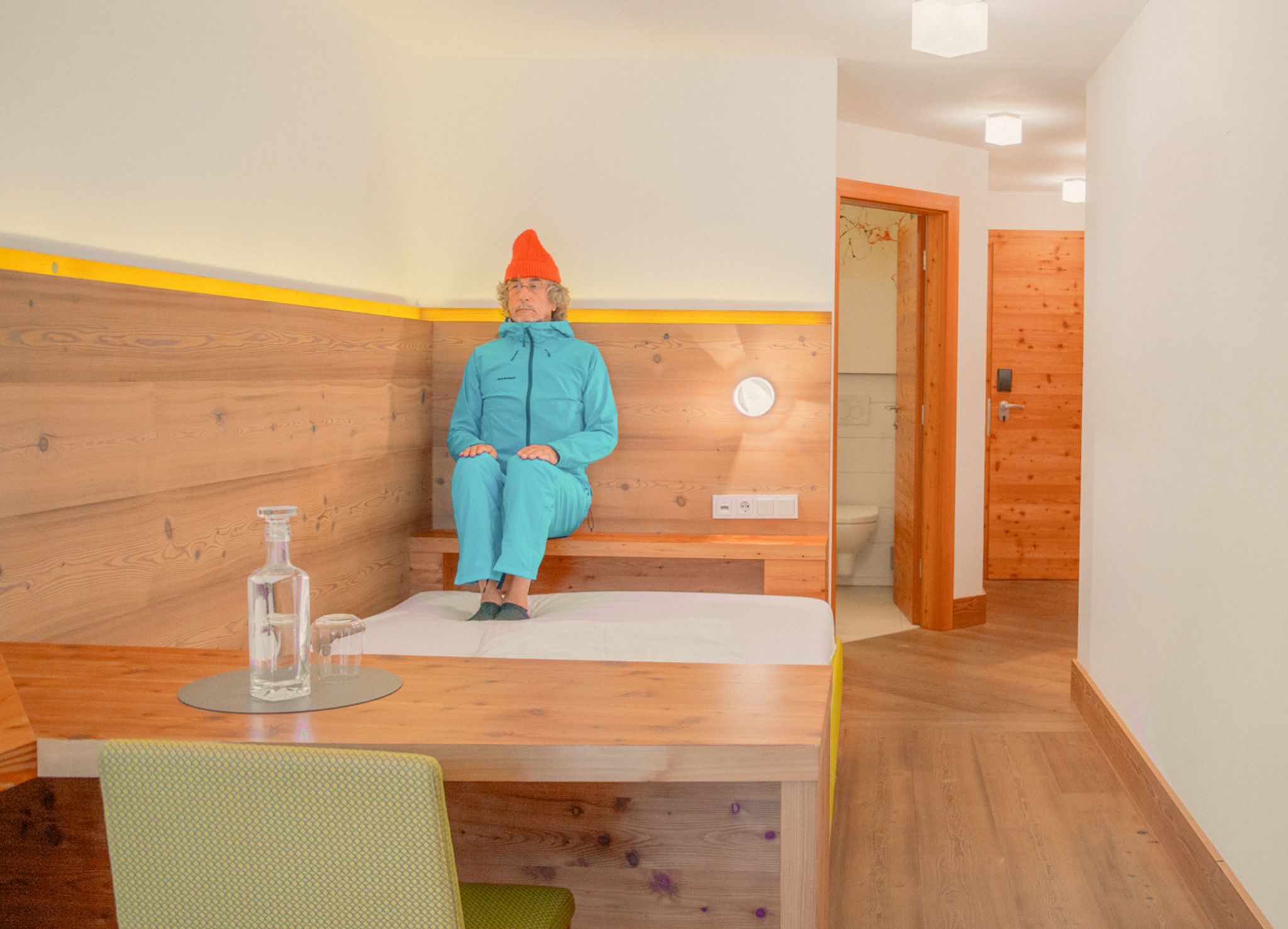 Ein Mann in einem blauen Anzug sitzt in einem modernen Zimmer im Glemmtalerhof in Hinterglemm.