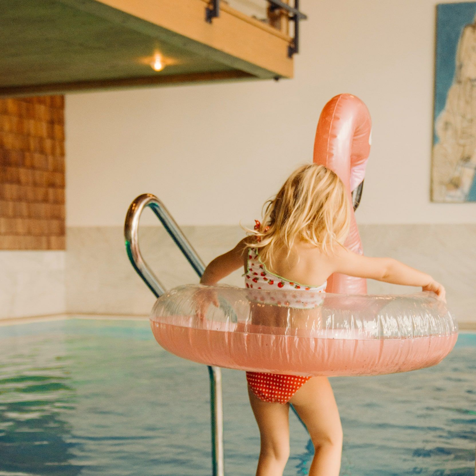 Ein Mädchen mit einem Flamingo-Schwimmreifen im Glemmtalerhof-Pool—Sommerfreude pur im Glemmtal!