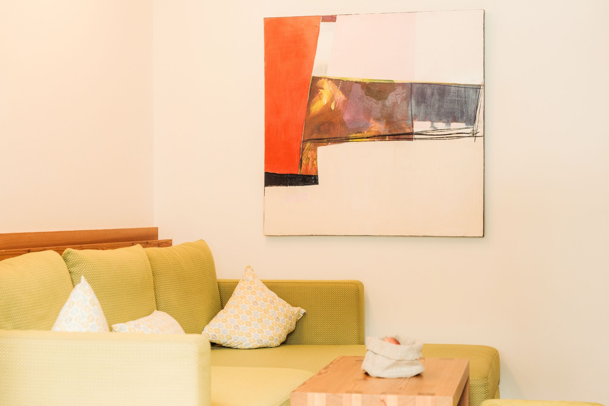 Ein gemütlicher Wohnbereich mit einem bunten Gemälde und einer einladenden Couch im Glemmtalerhof in Hinterglemm.