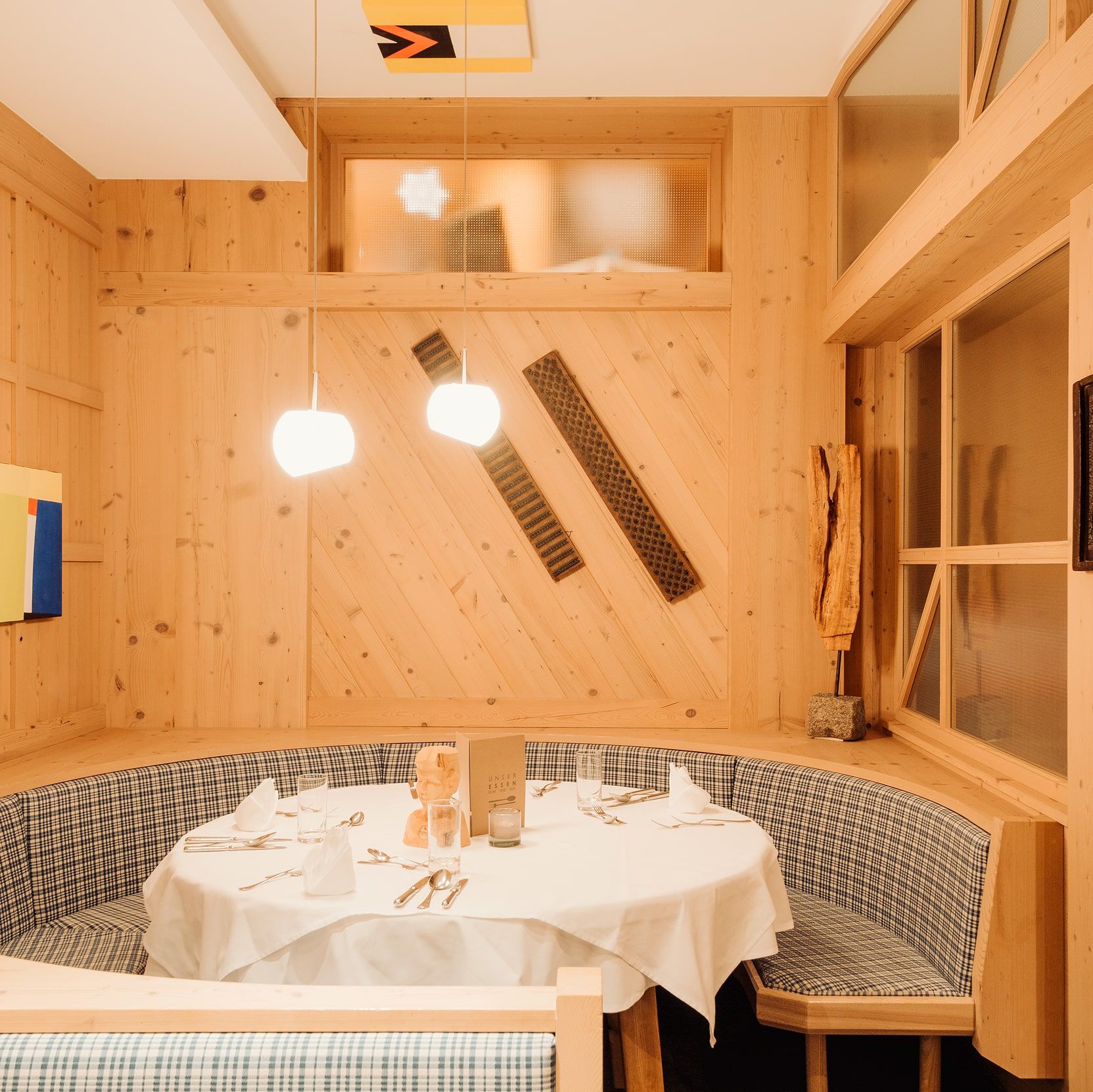 Gemütliche Ecke im Glemmtalerhof mit Holzverkleidung und modernem Design, ideal für ein festliches Dinner.