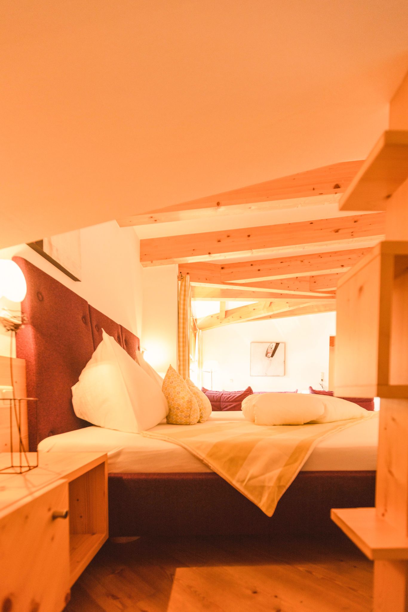 Ein gemütliches Schlafzimmer im Glemmtalerhof mit Holzdecke und Dekokissen.