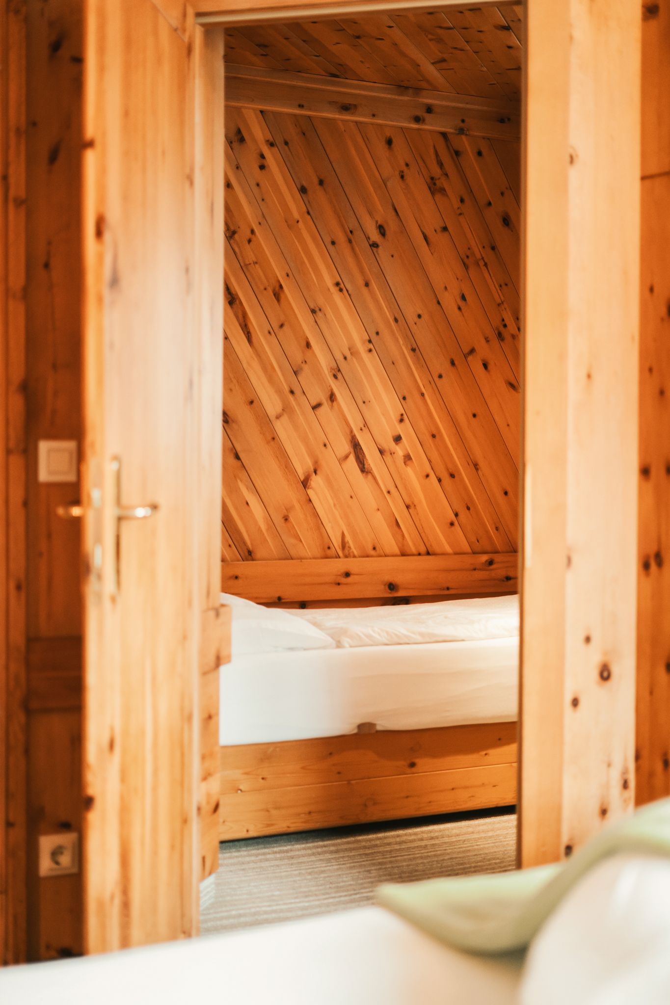 Helles Zimmer mit Holzverkleidung und einem Bett im Glemmtalerhof in Hinterglemm.